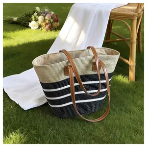 Close-up view of handmade woven straw beach tote bag with black and white stripes