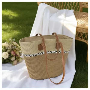 Woven straw tote bag with geometric pattern and brown leather straps for beach vacation