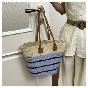 Detail of handmade woven straw tote bag for beach vacation with leather handles.