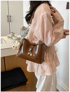 Elegante bruine leren emmer tas gedragen door een model in een stijlvolle café