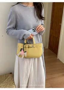 Dettaglio della borsa a mano gialla da donna con ciondolo a cavallo tenuta da modella