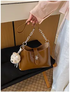 Elegante bruine glanzende onderarm schoudertas met zilveren ketting en een berenbedeltje