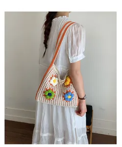 Bohemian style knitted shoulder bag featuring colorful crochet flowers for summer beach trips