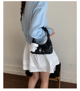 Borsa a spalla nera con stelle colorate e un ciondolo a forma di coniglio bianco