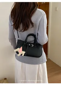 Vista dettagliata della borsa tote nera con ciondolo a cavallo indossata dalla modella