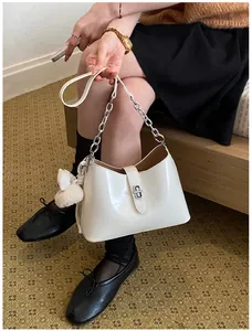 Elegante off-white hobo schoudertas met zilveren ketting getoond in een lifestyle setting