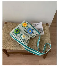 Boho style casual knit shoulder bag with crochet flower patches on a woven stool