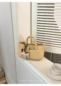 Borsa a mano giallo pallido sofisticata con ciondolo retrò su davanzale minimalista