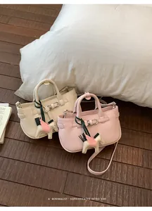 Vista dettagliata di mini borse tote rosa e beige con ciondoli pony su un pavimento in legno