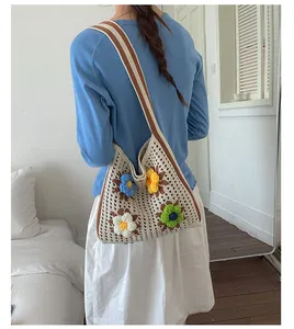 Model wearing hand-crocheted tote bag with colorful 3D flower decorations