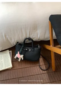 Dettaglio di una borsa tote in pelle nera minimalista con un ciondolo a forma di pegaso
