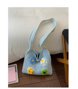 Detail view of light blue crochet shoulder bag featuring colorful knitted flowers