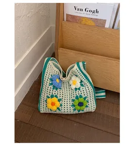 Macro view of floral knitted tote bag with colorful textured crochet details on wood