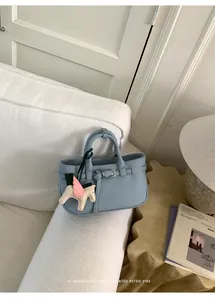 Elegante borsa tote in pelle azzurra con un grazioso ciondolo a forma di cavallo alato
