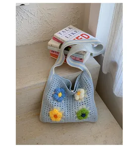 Detail view of light blue knit crochet tote bag with colorful flower decorations