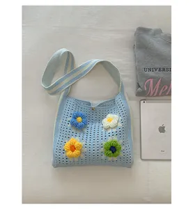 Close-up detail of light blue knitted tote bag featuring colorful 3D flower decorations