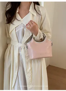 Vue détaillée d'un sac à main seau rose élégant avec poignées argentées porté par un mannequin