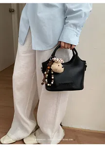 Détail d'un sac seau noir minimaliste pour le travail avec un charmant ours en peluche