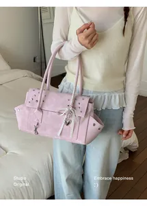 Detailansicht einer Frau mit einer stylischen rosa Nietentasche und Herzanhänger-Akzent.