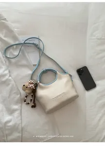 Vue détaillée du sac seau crème et bleu clair avec logo PANTOR et breloque en forme d'ours