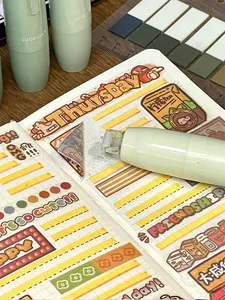 Macro view of light green push-button dot glue applicator used on a scrapbook page