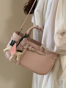 Borsa a mano in pelle martellata rosa con ciondolo a cavallo, indossata da una modella.