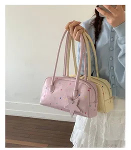 Primer plano de elegantes bolsos tipo almohada rosa y crema con motivos de estrellas.
