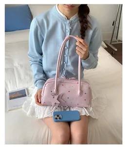 Bolso Boston rosa con estampados de estrellas de colores en un entorno de dormitorio.