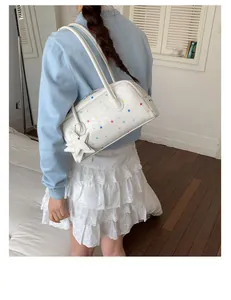Bolso blanco con estampado de estrellas de colores llevado por una modelo