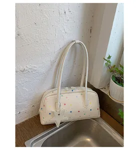 Primer plano de bolso bandolera blanco con estampados de estrellas y colgante de estrella