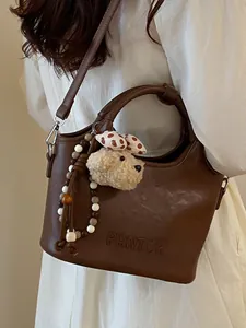 Sac seau à bandoulière en cuir marron vintage avec une peluche de chien mignon sur mannequin