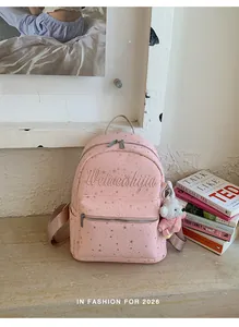 Vista detallada de la mochila rosa de lona con estrellas y llavero de oso