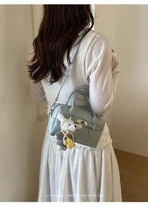 Sophisticated blue litchi pattern bowling bag on model with a cute plush dog charm