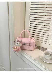 Pink lychee grain leather bowling bag with cute bunny keychain in a minimalist setting