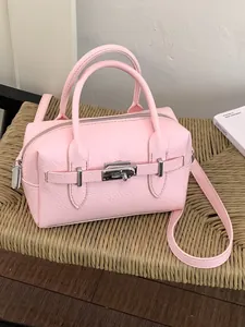 Stylish pink lychee pattern bowling handbag with silver lock shown on a woven chair