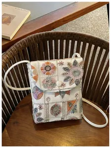 Vista dettagliata di una borsa a tracolla bianca con ricami floreali vintage chic.