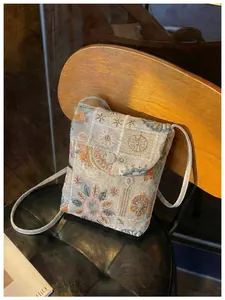 Primo piano di borsa a tracolla ricamata con motivi floreali in stile tradizionale cinese