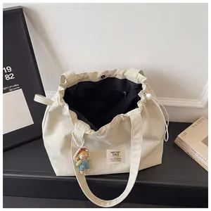 Detailed interior view of a large off-white canvas tote bag with black lining and pocket
