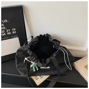 Detail view of a large capacity black checkered canvas tote bag with drawstring closure.