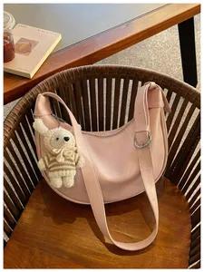 Detail of a pink faux leather dumpling bag on a wooden chair with a cute bunny charm