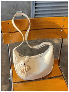 Close-up of a stylish white glossy hobo bag featuring a charming knitted rabbit pendant