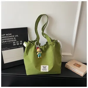 Spacious green checkered tote bag featuring a cute doll charm in a modern minimalist setting