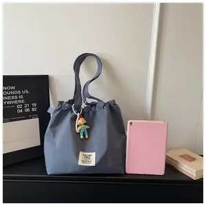 Fashionable blue grid canvas tote bag featuring drawstring closure and a cute doll pendant