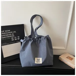 Stylish blue checkered canvas tote bag featuring a ruffled top and brand patch detail