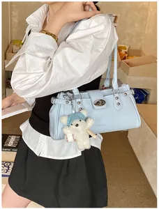 Gros plan d'un sac à bandoulière bleu clair élégant avec un adorable charme d'ours.