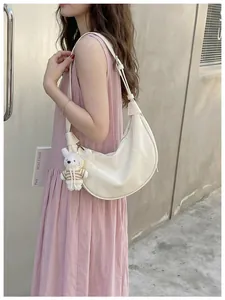 Stylish off-white crescent hobo bag for women worn with a pastel pink dress.
