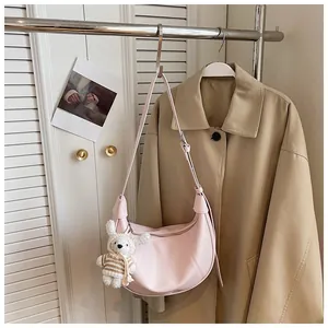 Close-up of a pink crescent dumpling bag with a cute bunny charm on a lifestyle background