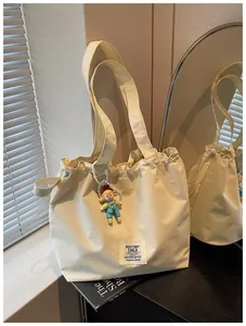 Cream-colored large capacity canvas tote bag with a cute cartoon girl charm detail