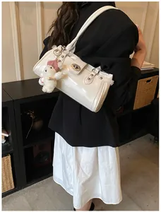 Sac à bandoulière rétro brillant crème élégant porté par un mannequin au look chic