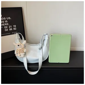Close-up of a light blue crescent crossbody bag compared with a green tablet for size.